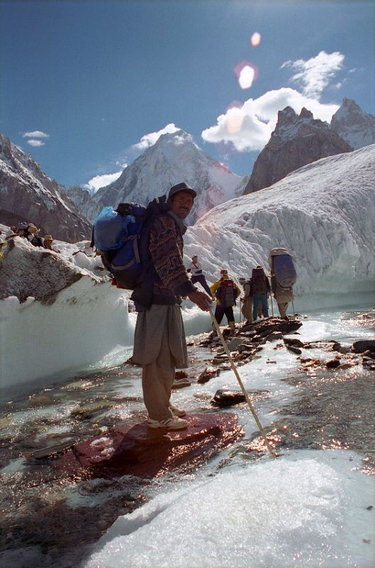 03 Porter Muhammad Khan Crossing A Small River On The Upper Baltoro Glacier With Gasherbrum IV Behind Porter Muhammad Khan crossed a small stream on the Upper Baltoro Glacier with Gasherbrum IV behind.